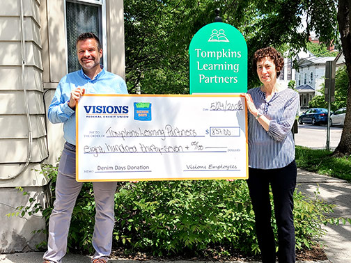 Visions provides a giant check to Tompkins Learning Partners for April Denim Days.