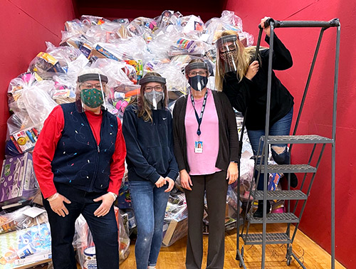 Visions employees from our Elmira office standing in front of a large pile of gifts with employees from The Arctic League.