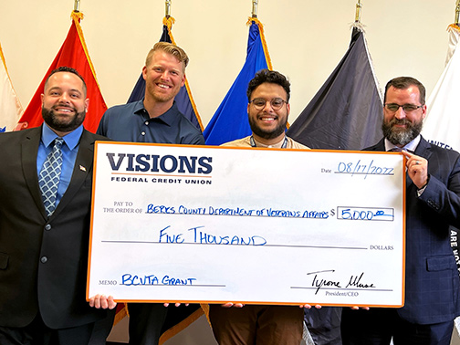 Gustavo (Community Development Liaison) and Jake (Regional Membership Manager) smile with members of the Berks County Department of Veteran Affairs as they all hold up a jumbo grant check for their BCVTA Grant Program.