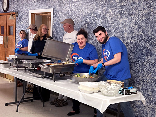 Visions employees Jocelyn (left) and Peter (right) serving delicious food to veterans in a cafeteria. 