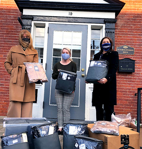 Visions employees pose with a Family Promise of Sussex County employee, all holding men's coats from the collection we donated.