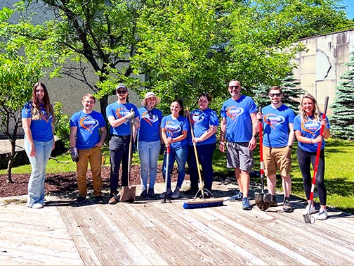 Visions employees take a break from volunteering at the Roberson Museum and pose with their gardening tools.