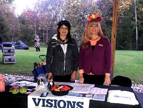 Visions employees stand in costume behind a festive table, with candy to hand out at the Día De Los Muertos festivities in Washington, NJ, hosted by the Washington Business Improvement District.