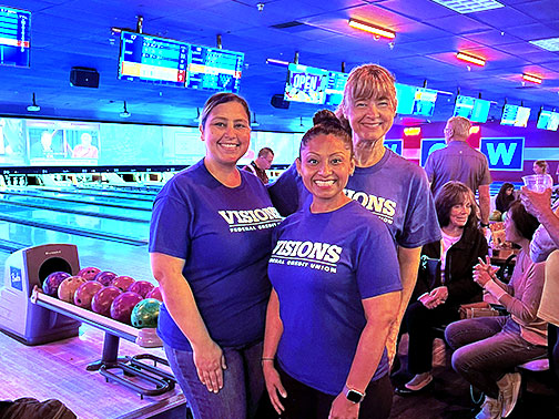 Three New Jersey employees pose for a picture in their blue Visions shirts at the bowling alley for Ethan & The Bean's Bowling Bash event.