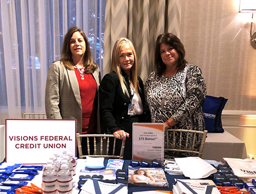 Members of the Visions New Jersey Business Development team smile at their sponsor table during the Bergen Food and Wine Experience in River Vale, NJ.