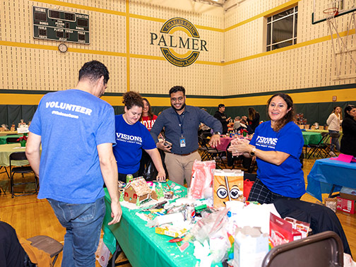 A group of Visions employees are pictured at a green table decorating their gingerbread house during the Habitat for Humanity of Lehigh Valley's Gingerbread Competition.