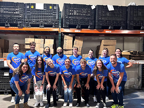 Visions high school interns line up for a picture at the CHOW warehouse while volunteering.