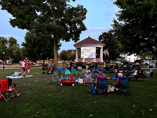 Residents of Westwood, NJ sit on blankets and in lawn chairs during sunset at Veteran's Park for free family movies.