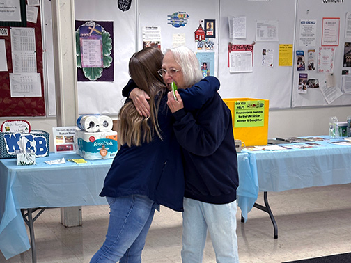 Pictured is Sarah (Community Development Liaison) embracing a member of My Brother's Keeper as she presents them with gift cards to a local craft store.