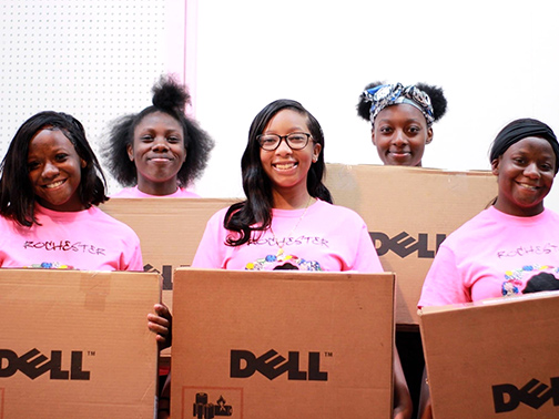 Members of the Rochester school-age girls mentoring program, Rochester Jewels, stand smiling with their newly purchased laptops from the Visions Cares grant.
