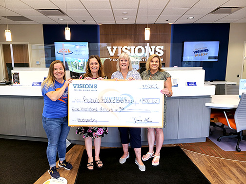 Pictured holding a jumbo check are Sarah (Visions Community Development Liaison), Traci (AIS Reading Teacher at Roxboro Road Elementary and Co-Founder of the school's food pantry), Susan (recently retired teacher and another Co-Founder of the food pantry), and Sarah (Visions Branch Manager - Cicero).