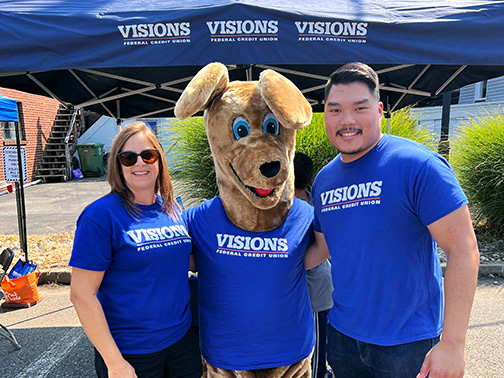 Two of our New Jersey employees smile with Kirby, all in matching blue Visions shirts.