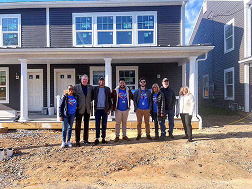 Visions employees, representatives from Habitat for Humanity of Berks County, and the home recipient, standing in front of a home construction site.