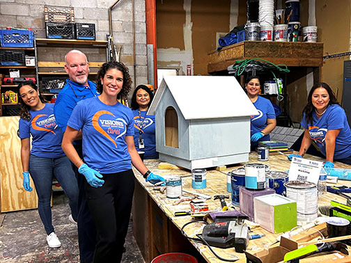 Visions employees pictured in a workshop in front of a painted and built doghouse.