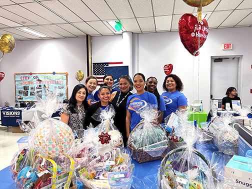 Visions employees pictured behind a table full of baskets and balloons to give out to pregnant women and breastfeeding mothers to celebrate their success.
