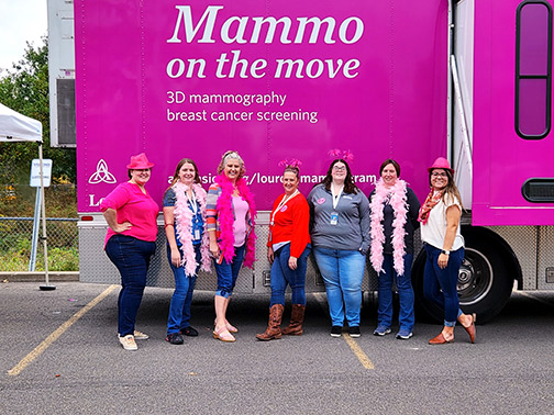 Visions employees Jocelyn, Mariah, Hilary, Katherine, Crystalyn, Jessica, and Megan all pictured in front of the Mammogram Van in the Norwich parking lot.