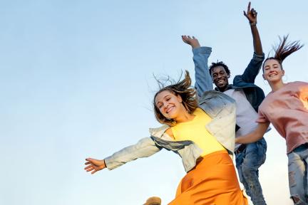 Image of three kids jumping with a blue sky background