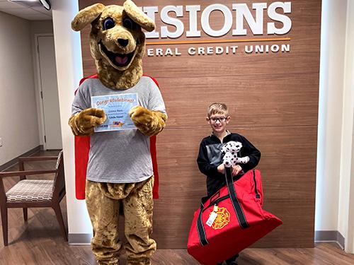 Connor, holding his fireman utility bag and stuffed Dalmatian, posing with Kirby (who is holding his Little Heroes certificate)