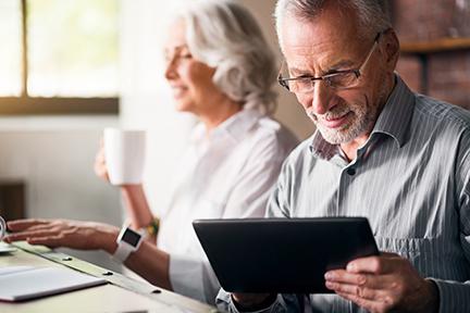 Couple sitting at table using tablet and drinking coffee