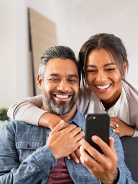Couple smiling, looking at phone
