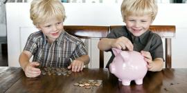 Two kids placing coins in a piggy bank
